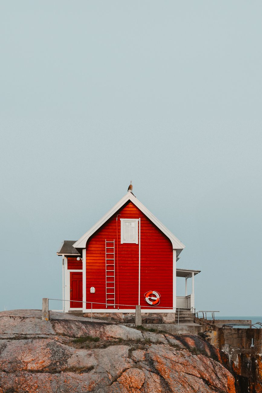 Minimalist Nordic wooden cabin perched on rocky fjord